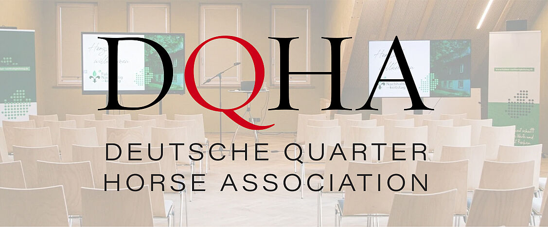 Leerer Veranstaltungsraum mit Stuhlreihen, Bühne und Präsentationsbildschirmen; darüber das Logo der Deutschen Quarter Horse Association (DQHA).