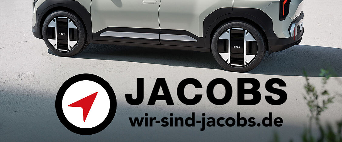 Modernes Sponsor-Motiv von „Jacobs“ mit markantem Logo und rotem Pfeilsymbol, kombiniert mit der Website wir-sind-jacobs.de. Im Hintergrund ein modernes Fahrzeugdetail, das Mobilität, Innovation und Zukunftsorientierung vermittelt.