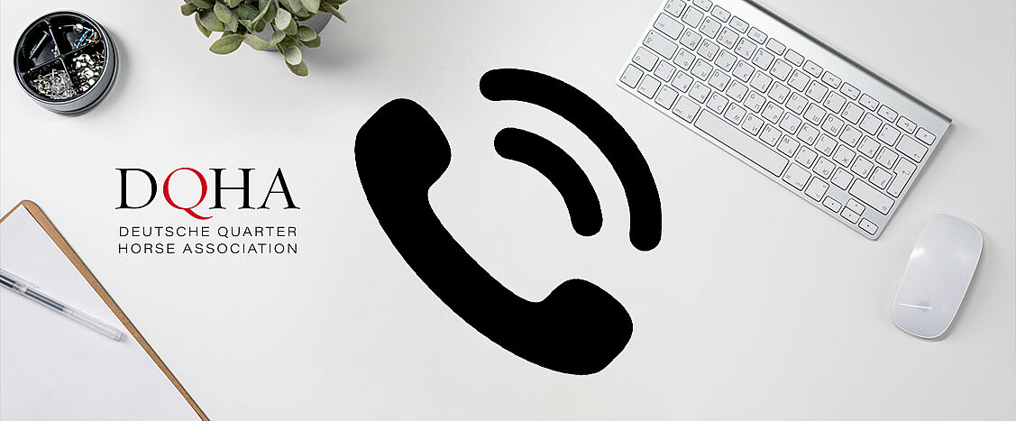 Auf einem hellen Schreibtisch liegen eine Tastatur, eine Maus, ein Klemmbrett, ein Stift und ein kleiner Pflanzen­topf. Links ist das Logo der Deutschen Quarter Horse Association (DQHA) zu sehen. In der Mitte des Bildes befindet sich ein großes schwarzes Telefonhörer-Symbol, das auf Kontakt oder telefonische Erreichbarkeit hinweist.