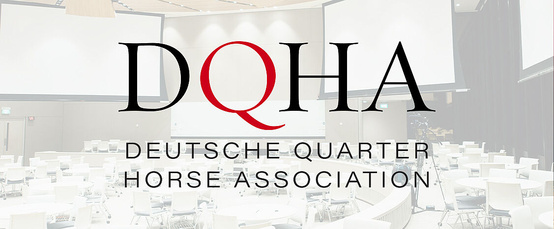 Logo der Deutschen Quarter Horse Association mit den Buchstaben „DQHA“, rotem „Q“ und dem Schriftzug „DEUTSCHE QUARTER HORSE ASSOCIATION“ vor einem hellen, unscharfen Hintergrund eines Veranstaltungsraums.